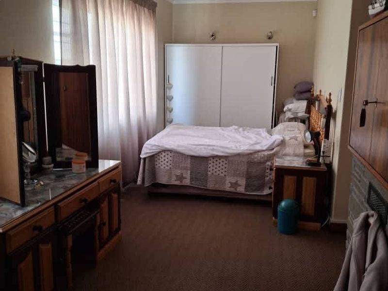 A functional bedroom featuring carpeted flooring, a built-in wardrobe, and neutral wall finishes, offering a comfortable and practical living space.
