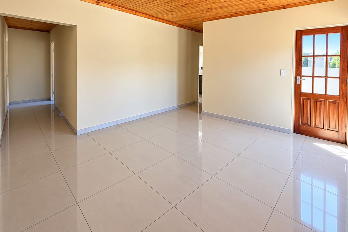 Spacious, empty living area featuring polished porcelain floor tiles and a warm timber tongue and groove ceiling, leading to an entrance door.