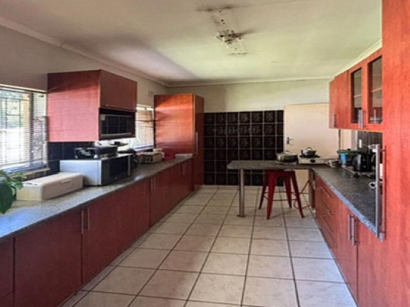 A spacious kitchen featuring extensive built-in cabinetry, tiled flooring, and a tiled backsplash, offering a functional layout with potential for modern updates.