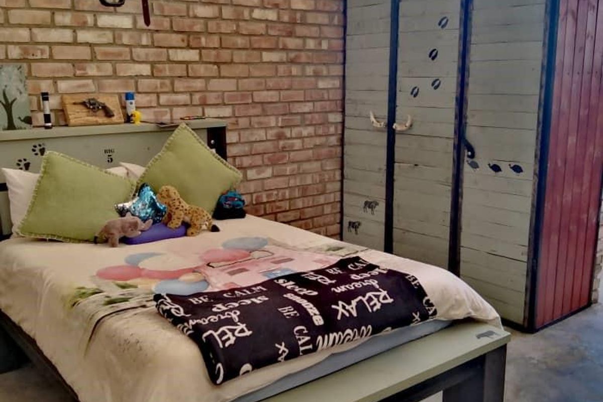 Rustic bedroom featuring exposed brick walls, high-pitched corrugated metal roofing, and industrial-style built-in cabinetry.