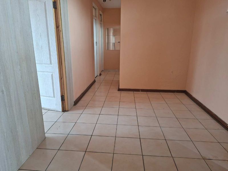 An empty hallway featuring tiled flooring and multiple internal doors, providing access to various rooms within the apartment.