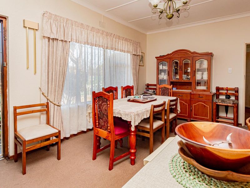 A dining room featuring a large window with curtains, a security gate leading to the exterior, and coved ceilings.