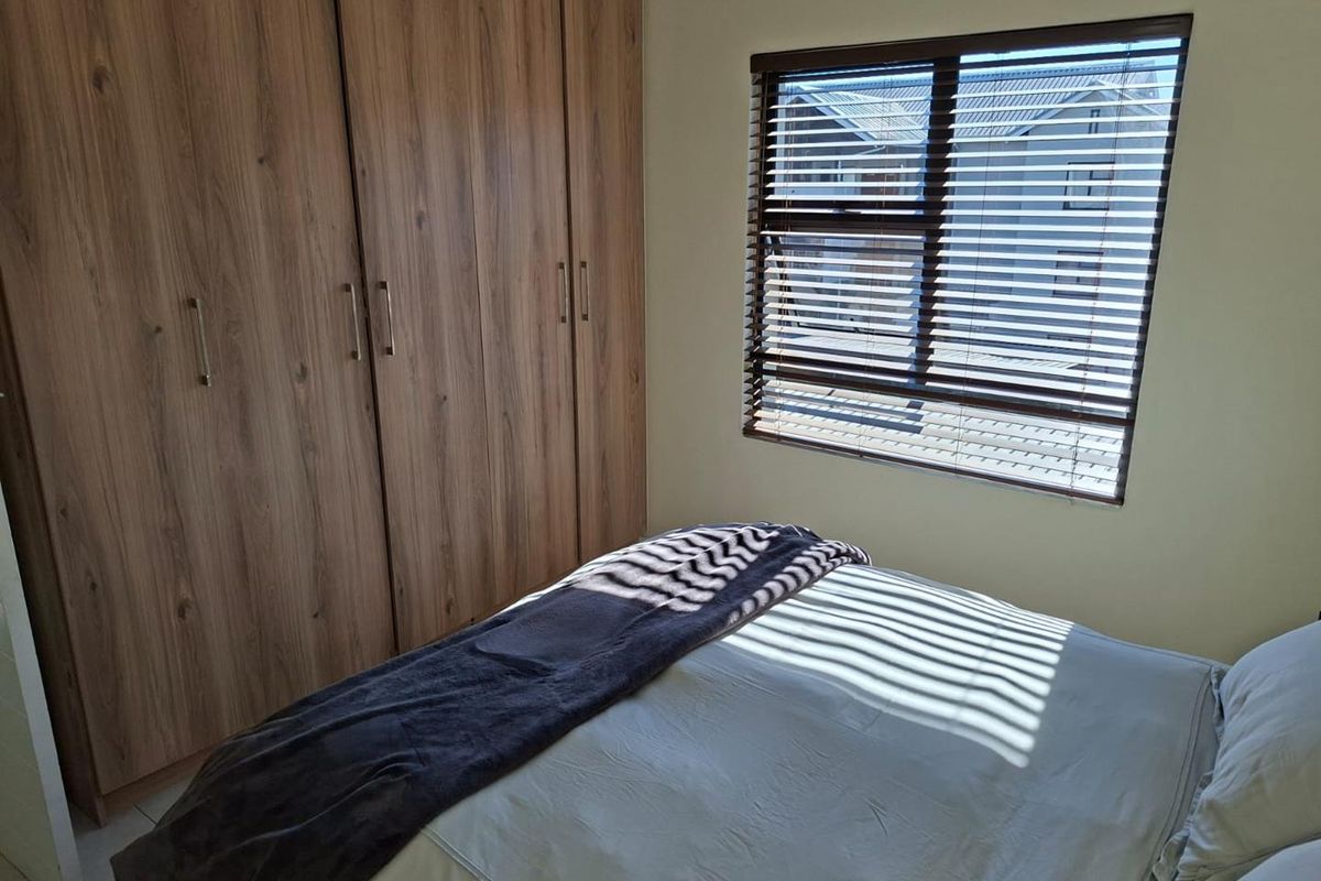 A well-maintained bedroom featuring built-in wooden wardrobes and venetian blinds, offering a clean and functional living space.
