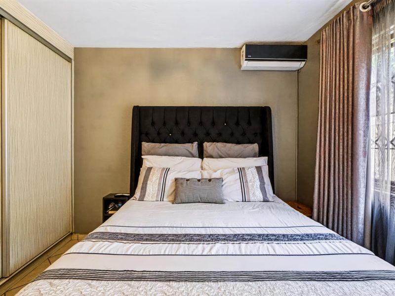 A bedroom featuring tiled flooring, a built-in wardrobe, and a wall-mounted split-system air conditioning unit.