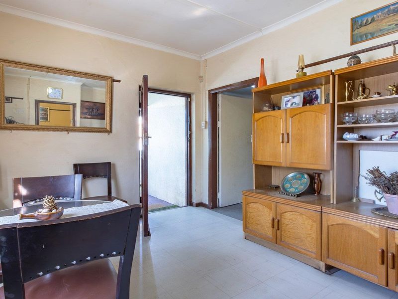 A living area featuring tiled flooring and traditional timber door frames, offering a functional space with potential for modern updates.