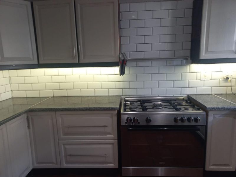 A functional kitchen featuring shaker-style cabinetry, granite countertops, a subway tile backsplash, and a stainless steel gas stove with an integrated oven.