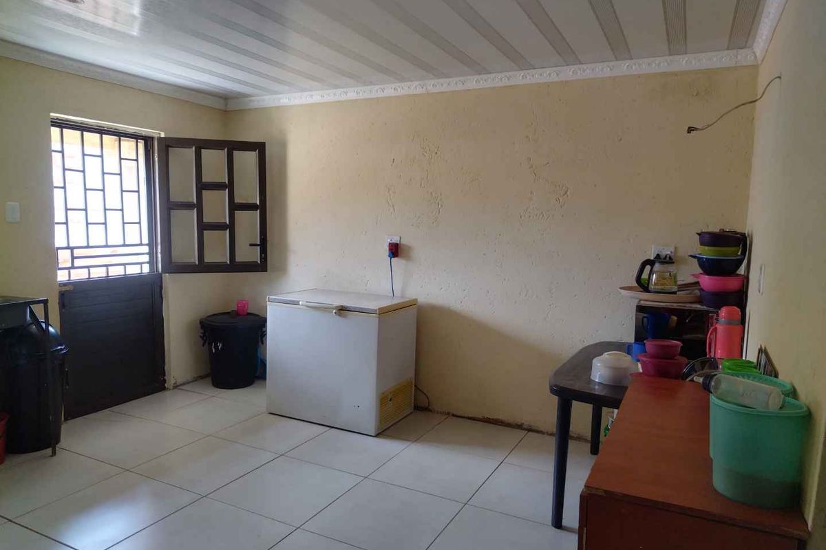 A functional utility or kitchen space featuring tiled flooring, a security gate, and basic wall finishes, suitable for renovation or storage use.
