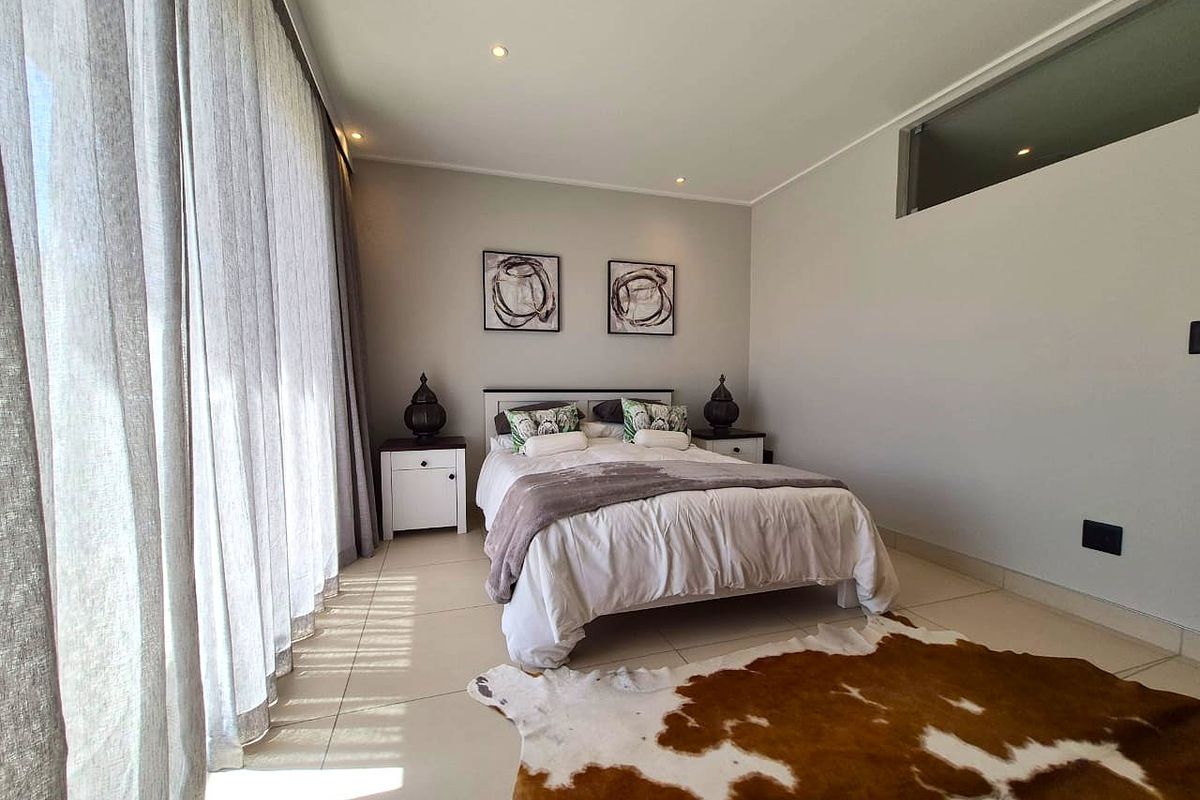 A well-maintained bedroom featuring neutral walls, tiled flooring, recessed lighting, and a high-level transom window for natural light.