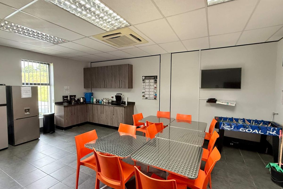 A functional office breakroom featuring built-in cabinetry, tiled flooring, recessed ceiling lighting, and a ceiling-mounted air conditioning unit.