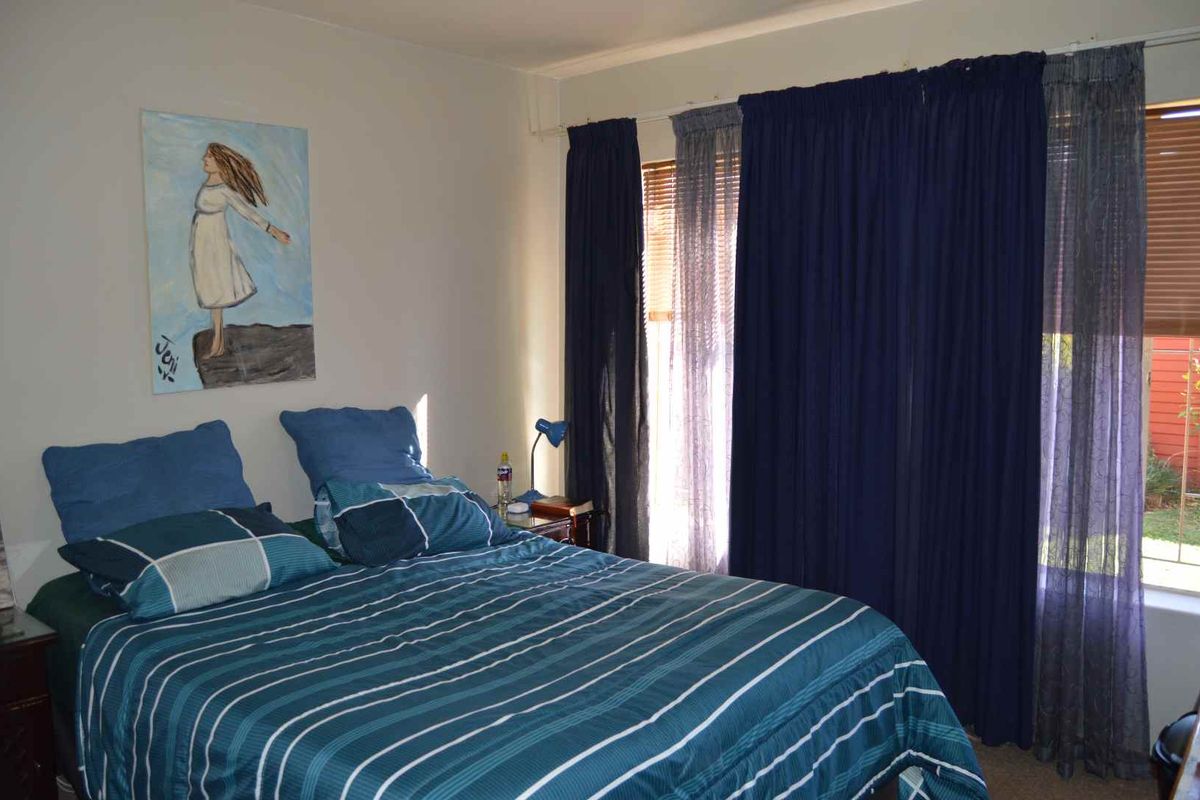 A standard bedroom featuring a window with curtain tracks, providing natural light and access to the exterior view.