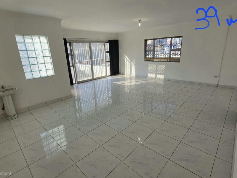 Spacious open-plan office area featuring tiled flooring, a private pedestal basin, and large sliding doors providing natural light and access.