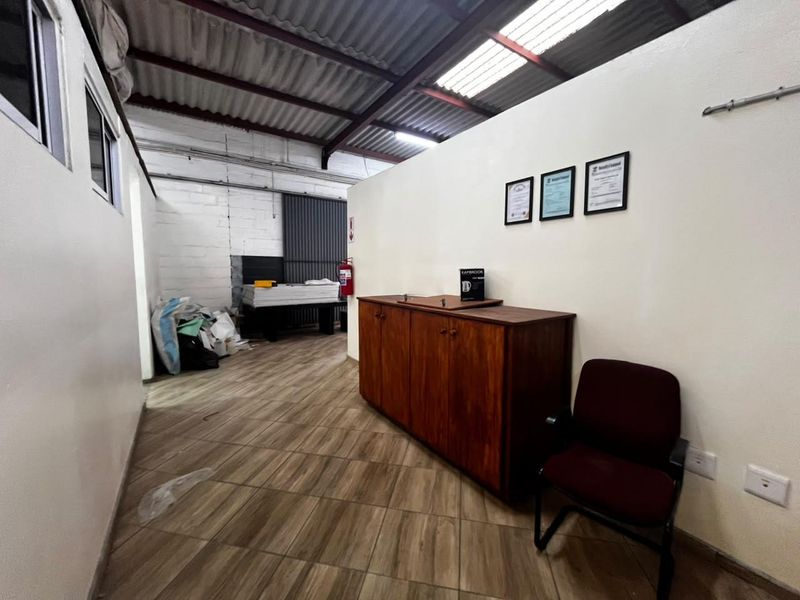 Industrial utility space featuring tiled flooring, exposed brick walls, and a corrugated metal roof with integrated skylight for natural illumination.