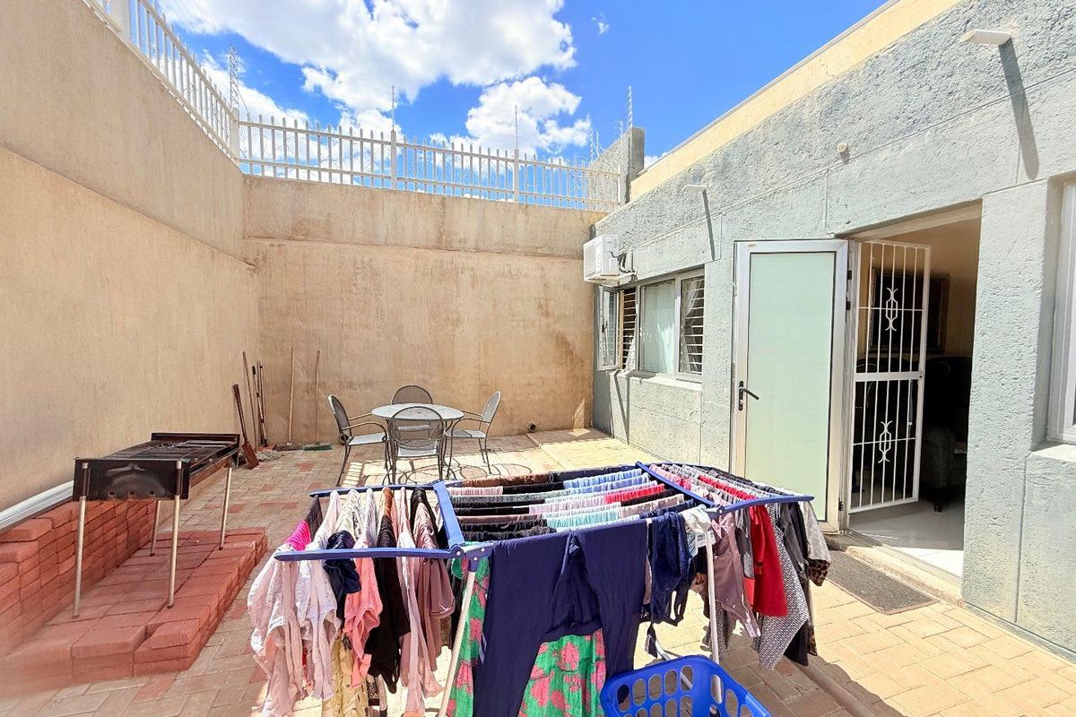 A private rear courtyard featuring paved flooring, a built-in brick braai area, and direct access to the interior living space.