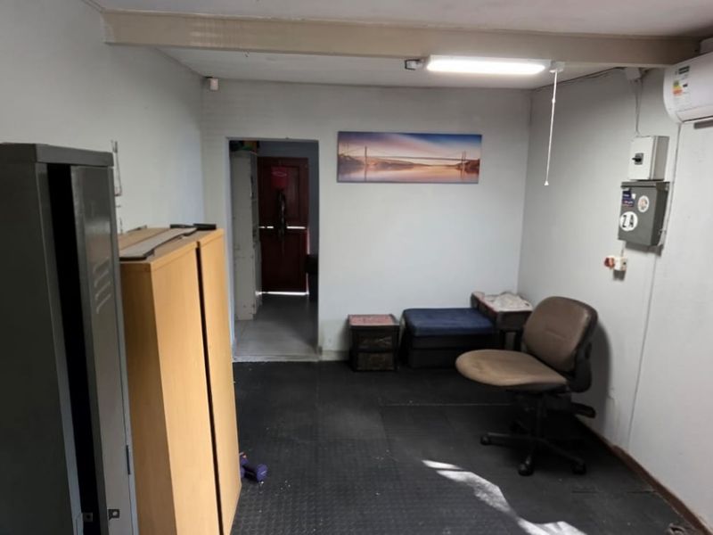 A functional utility space featuring a wall-mounted air conditioning unit, electrical distribution board, and durable flooring, suitable for storage or a home office.