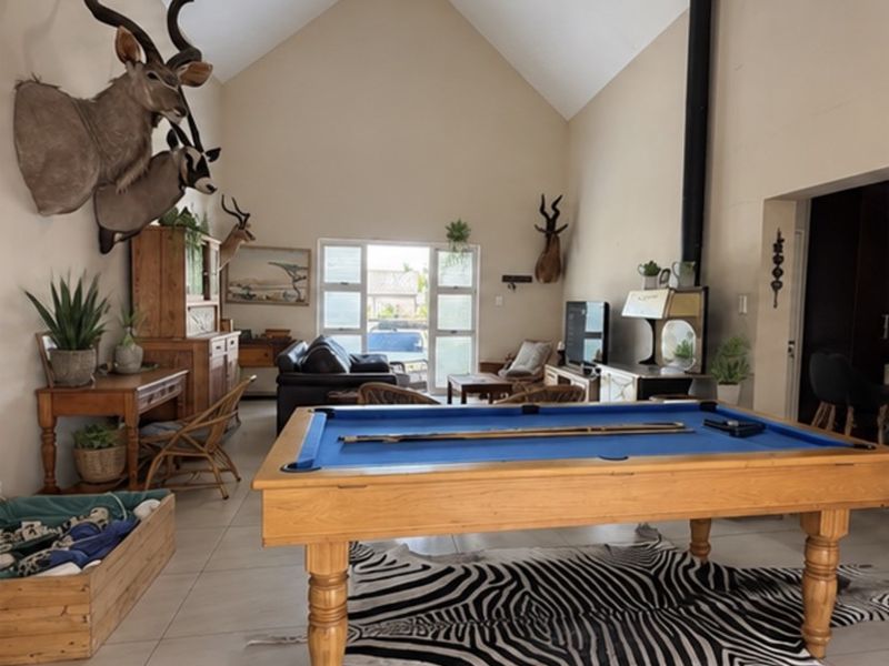 Spacious living area featuring a high vaulted ceiling, tiled flooring, and a prominent freestanding fireplace, offering a versatile open-plan layout.