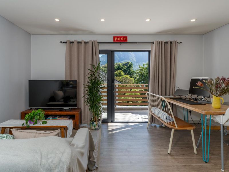 Bright living area featuring modern laminate flooring, recessed lighting, and a sliding glass door providing access to a balcony with scenic mountain views.