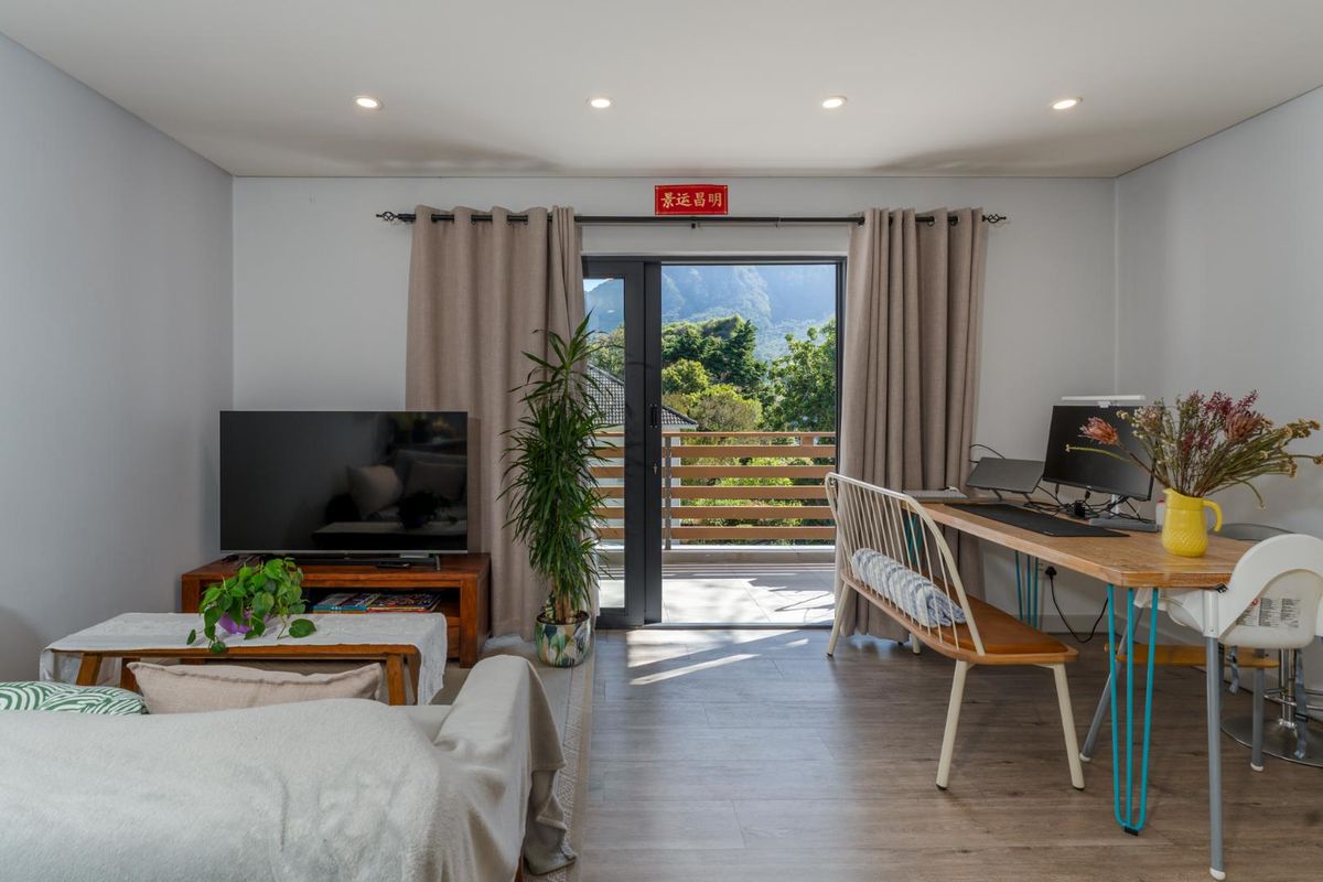 Bright living area featuring modern laminate flooring, recessed lighting, and a sliding glass door providing access to a balcony with scenic mountain views.