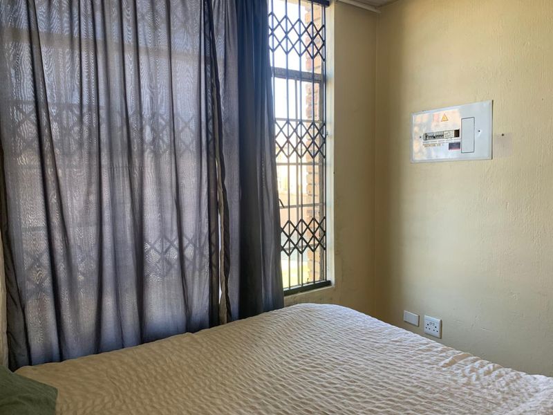 Bedroom featuring a window with a security gate and a wall-mounted electrical distribution board.