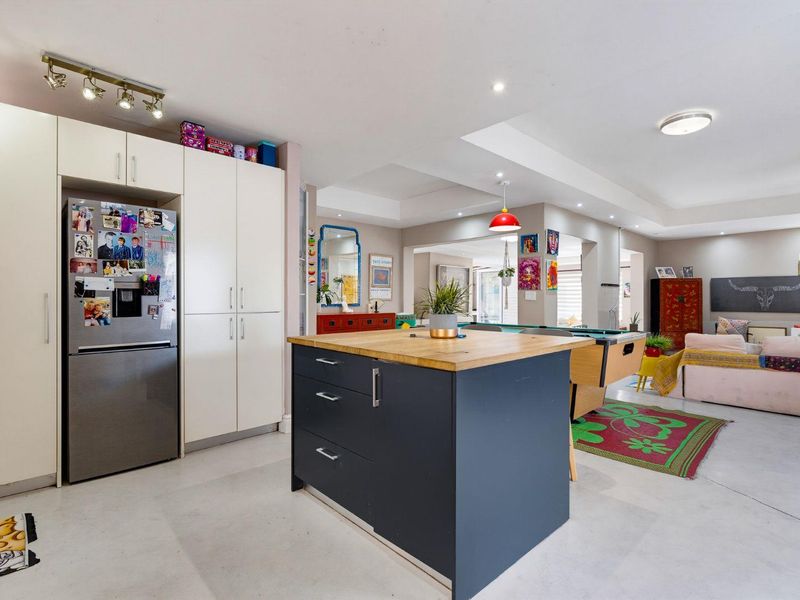 Spacious open-plan living area featuring a modern kitchen with a central island, sleek cabinetry, and polished concrete flooring throughout.