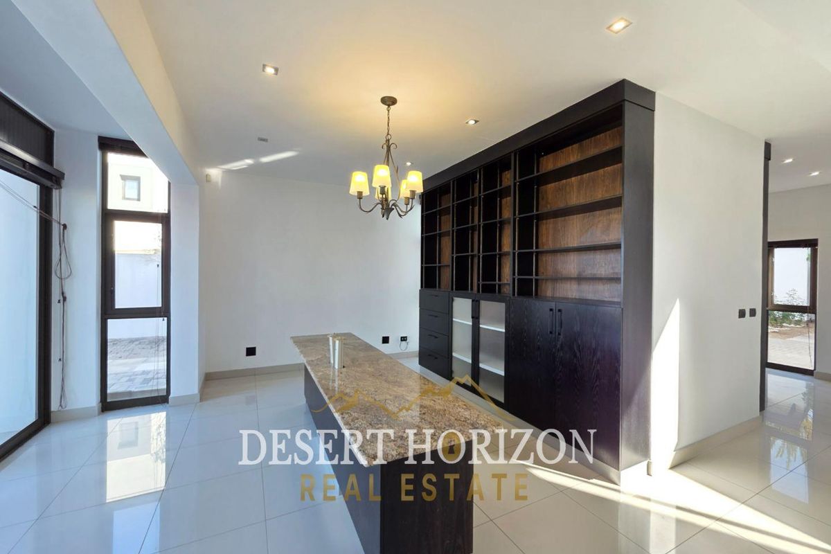 Spacious living area featuring built-in dark wood cabinetry, a granite-topped island, recessed lighting, and large windows providing ample natural light.