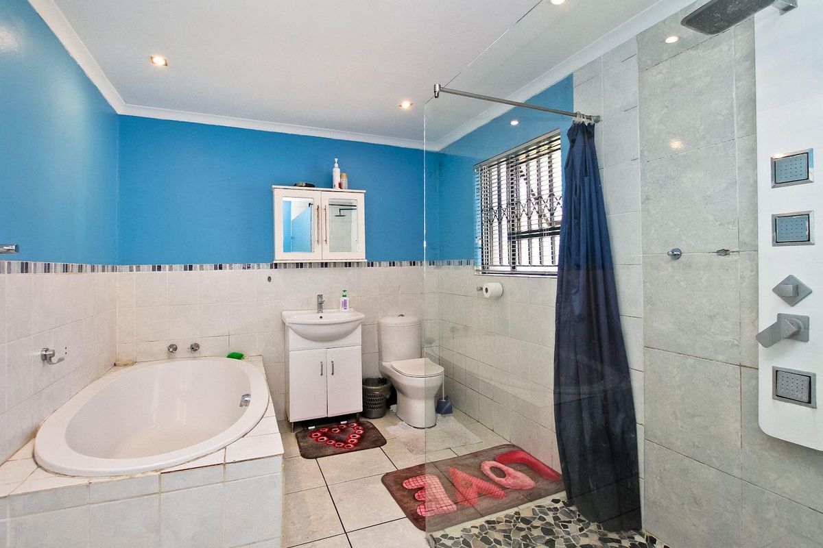 A functional bathroom featuring a built-in bathtub, a separate shower enclosure with a multi-jet panel, vanity sink, and toilet.