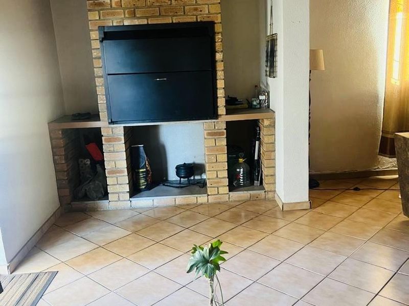 Living area featuring a prominent built-in brick fireplace with storage alcoves, tiled flooring, and a timber-clad ceiling.