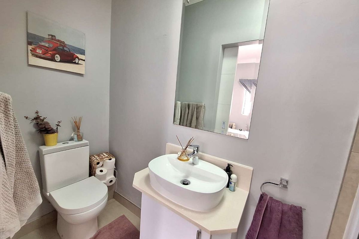 A compact bathroom featuring a modern vessel sink vanity, a wall-mounted mirror, and a standard toilet.