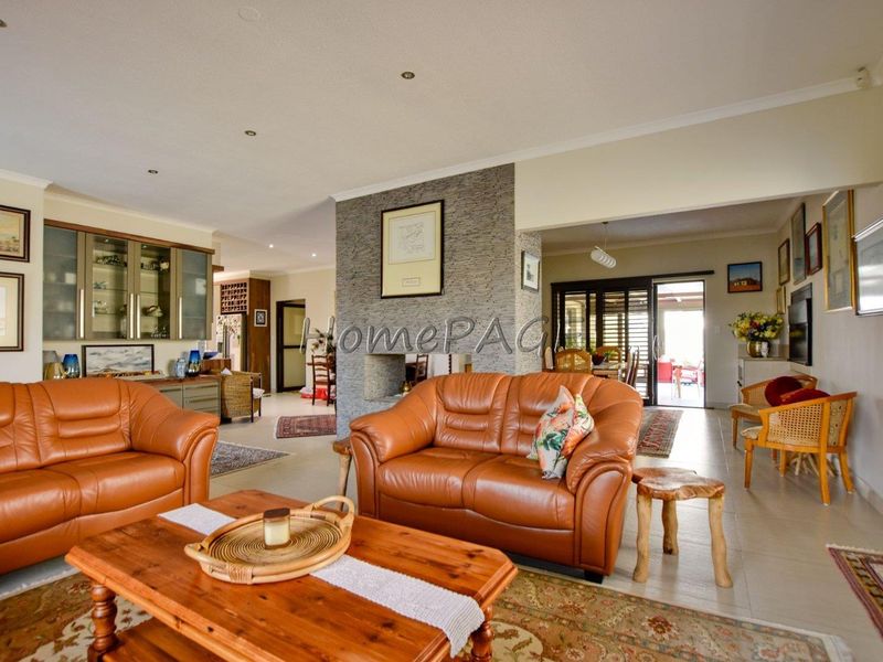 Spacious open-plan living area featuring a central stone-clad fireplace, tiled flooring, and seamless flow to the outdoor patio through sliding glass doors.