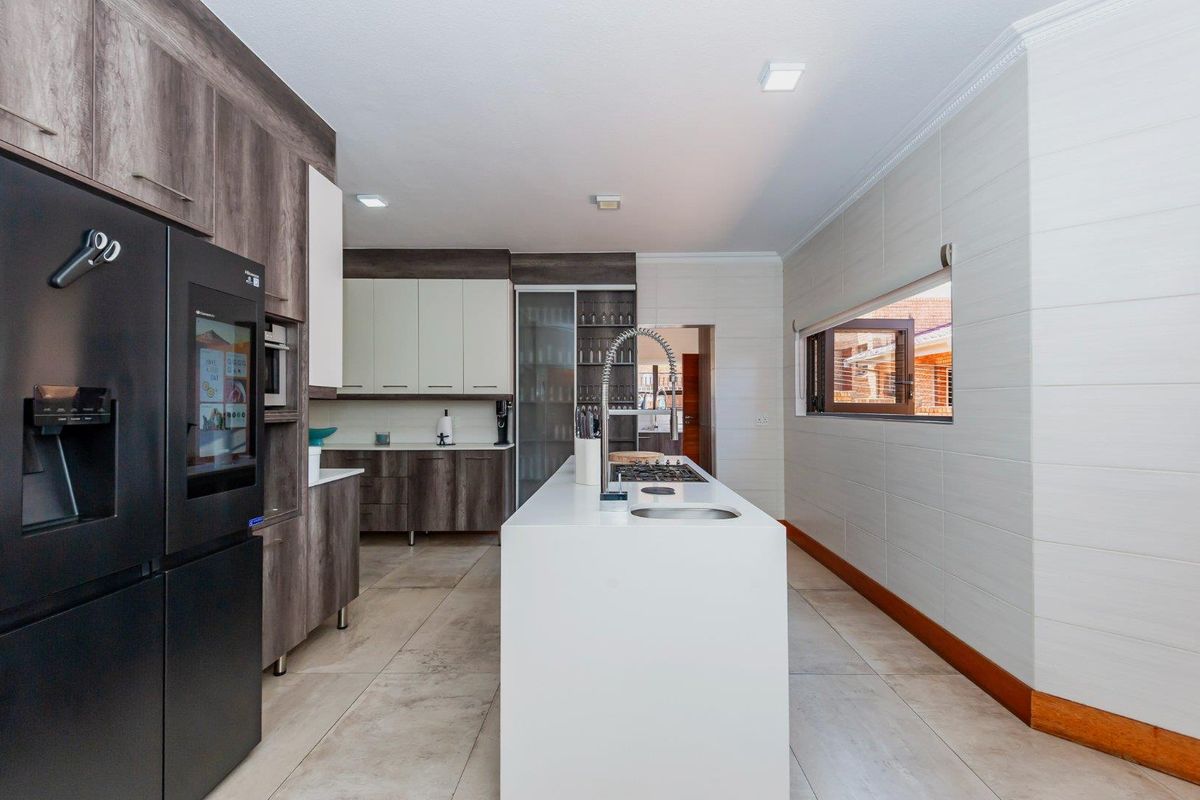 Modern kitchen featuring a central island with a built-in cooktop, sleek cabinetry, tiled flooring, and integrated appliances.