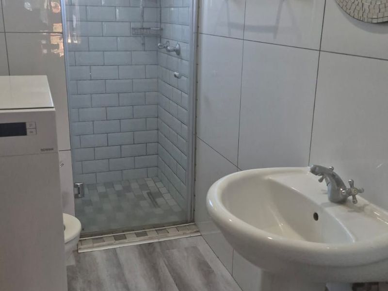 Modern bathroom featuring a pedestal basin, a glass-enclosed shower with subway tiling, and durable wood-look vinyl flooring.