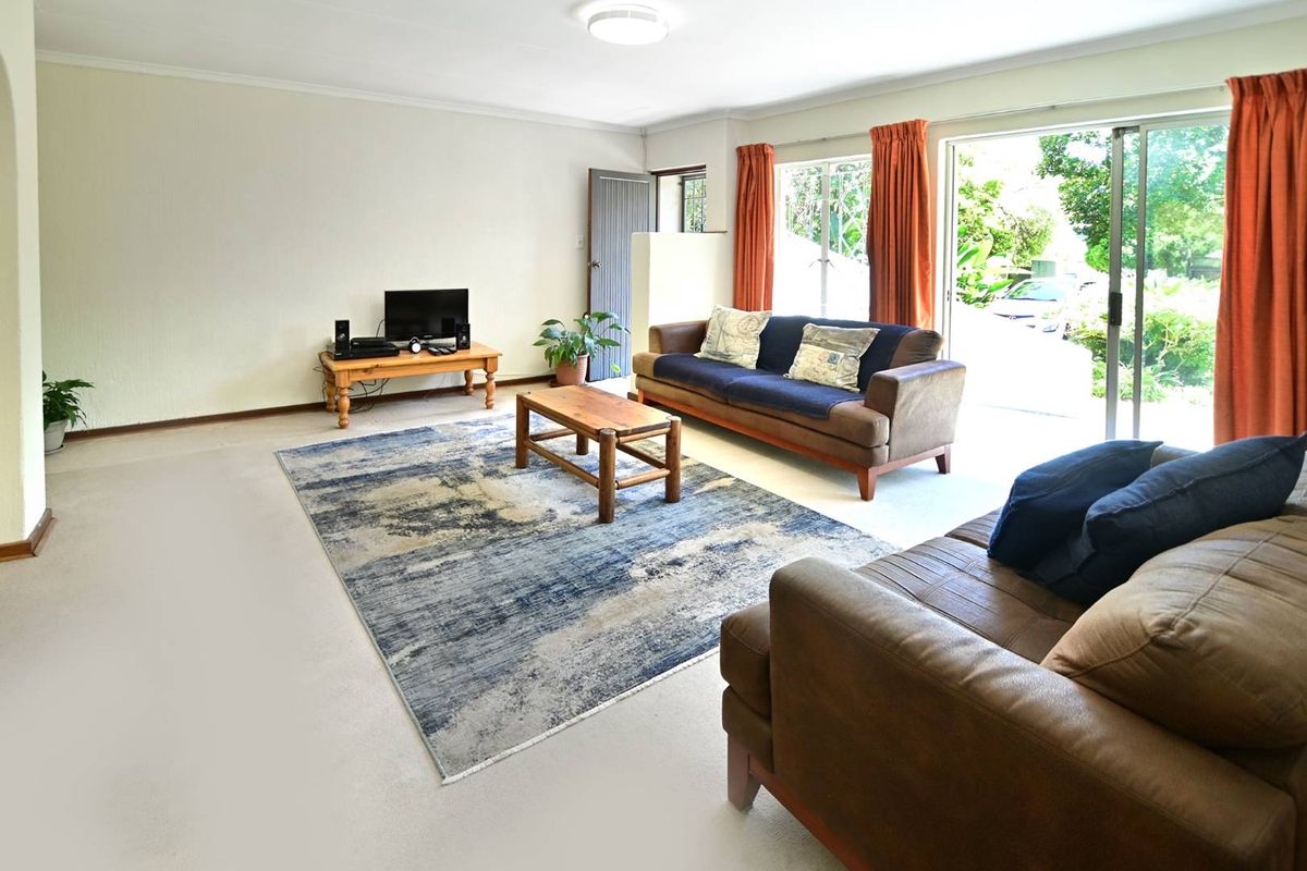 A spacious living room featuring neutral carpeting, a ceiling light fixture, and large sliding glass doors providing direct access to the outdoor area.