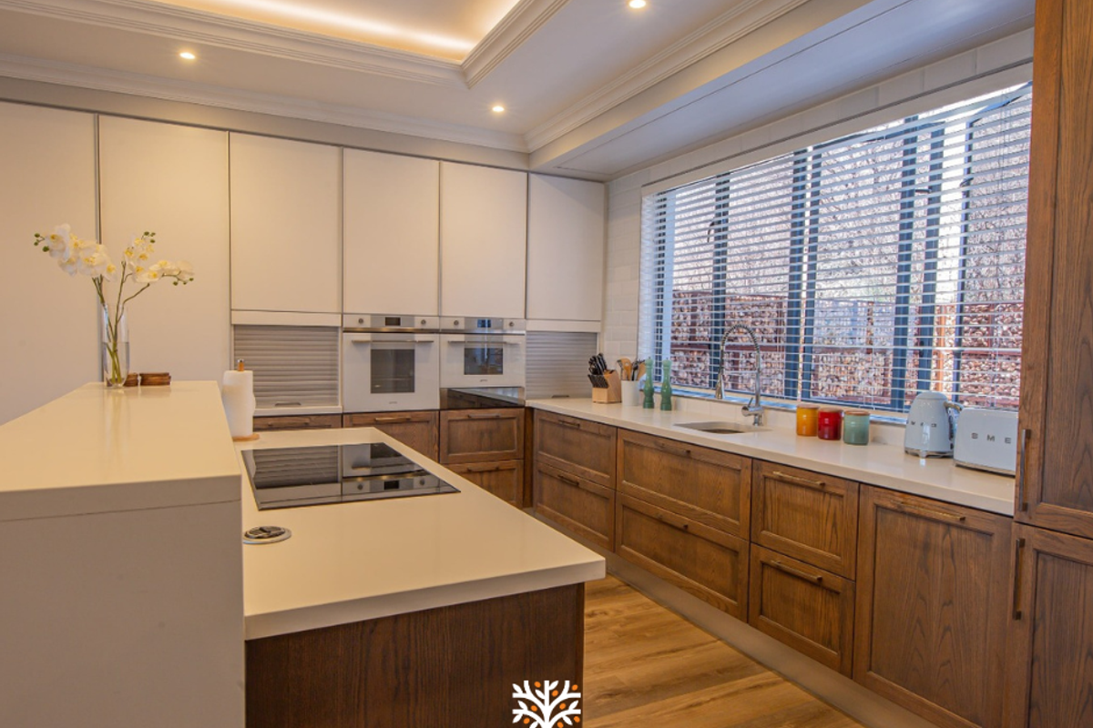 Modern kitchen featuring high-end cabinetry, integrated appliances, stone countertops, and recessed ceiling lighting with a large window providing natural light.