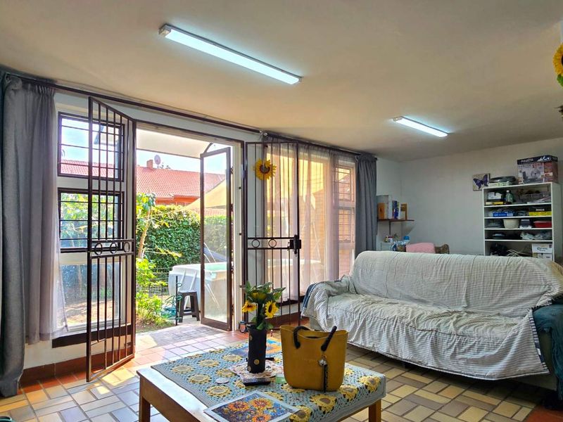 A living room featuring tiled flooring and direct access to an outdoor patio area through security-fitted glass doors.