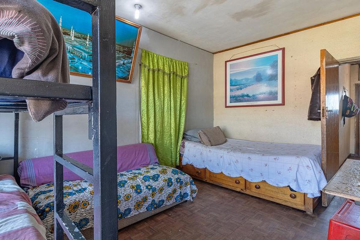A bedroom featuring parquet flooring and a standard door, showing signs of wear and requiring cosmetic updates.