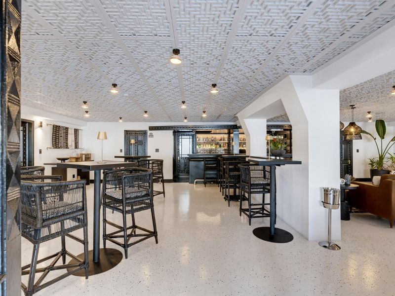 A stylish, well-maintained bar area featuring a decorative ceiling, modern epoxy flooring, and a built-in service counter.