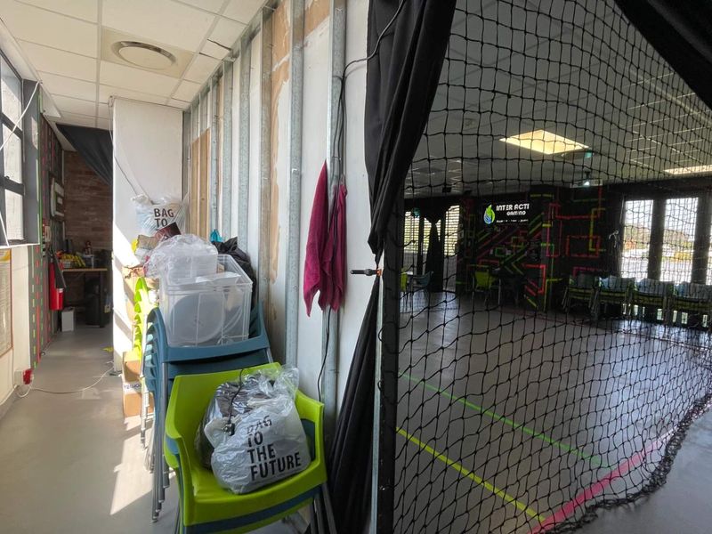 Indoor sports facility featuring vinyl flooring, safety netting, and unfinished wall framing, suitable for recreational or commercial use.