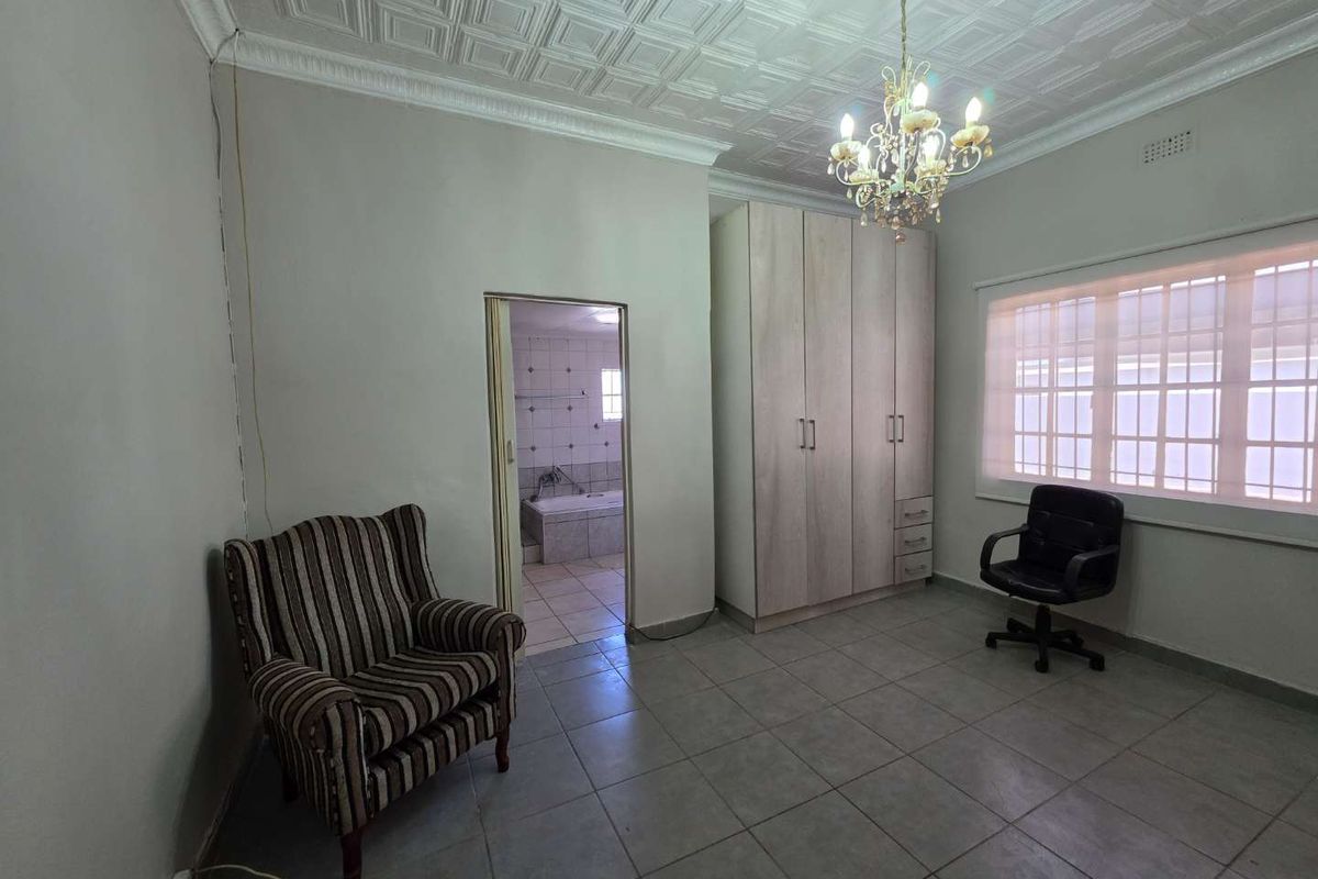 Spacious bedroom featuring built-in cabinetry, tiled flooring, decorative ceiling detail, and an en-suite bathroom access.