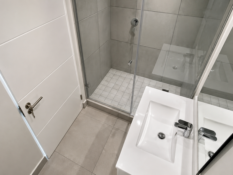 Modern bathroom featuring a glass-enclosed shower with tiled flooring and a contemporary wall-mounted basin with chrome fixtures.