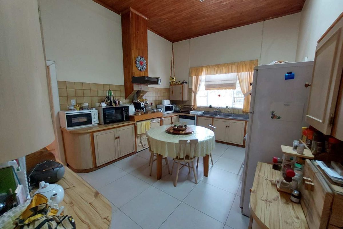 A dated kitchen featuring timber ceiling paneling, tiled flooring, and built-in cabinetry with a central dining area.