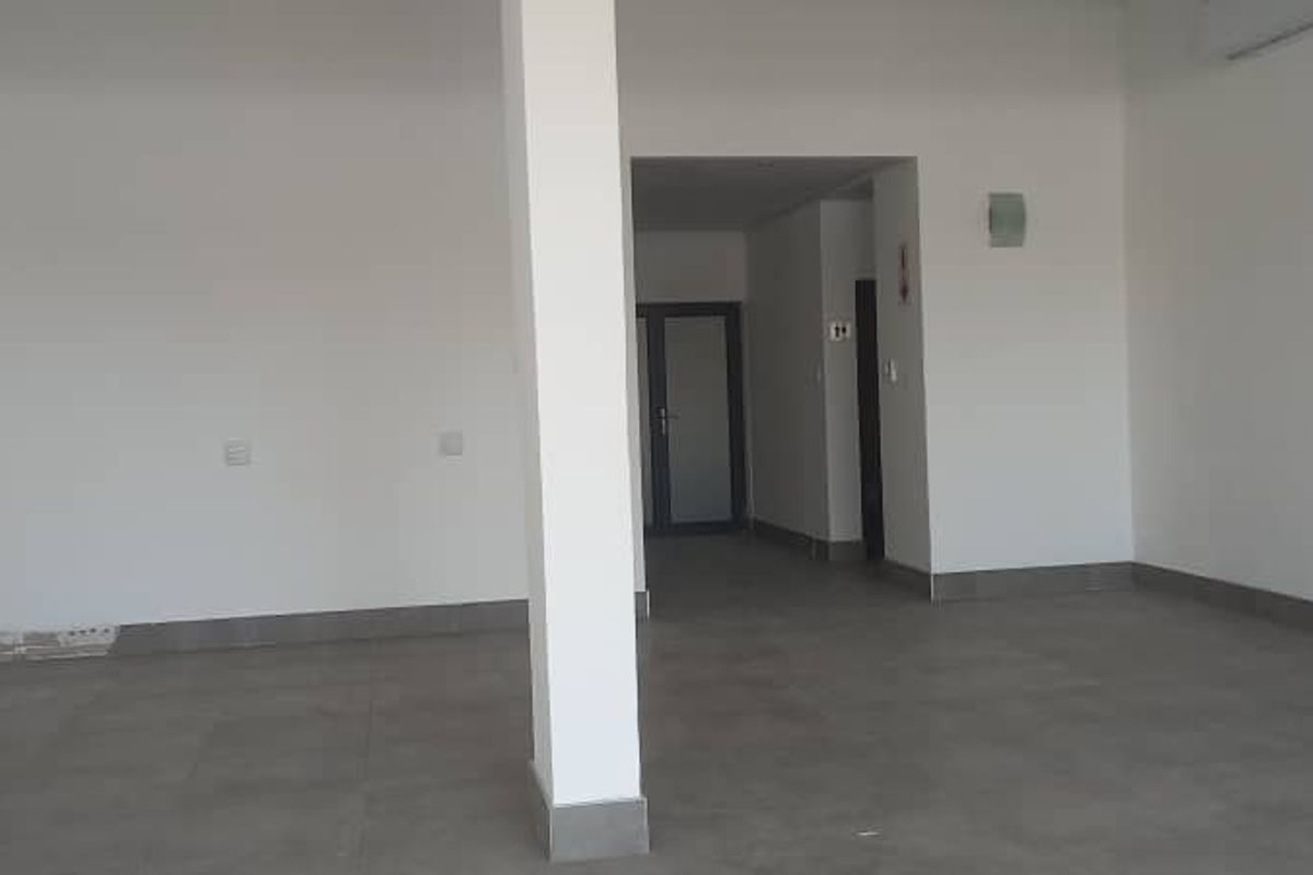 An empty open-plan retail space featuring tiled flooring, a central structural column, and neutral walls, ready for custom fit-out.