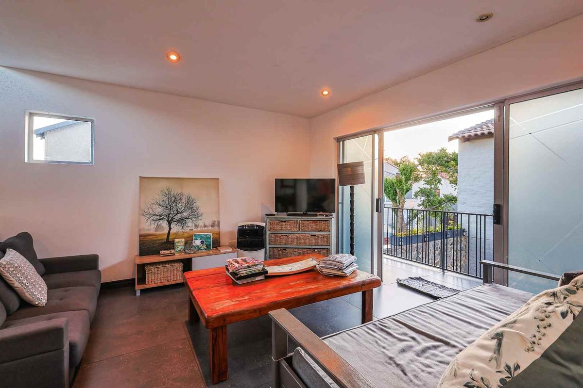 A comfortable living room featuring tiled flooring and large sliding glass doors that open onto a private balcony.