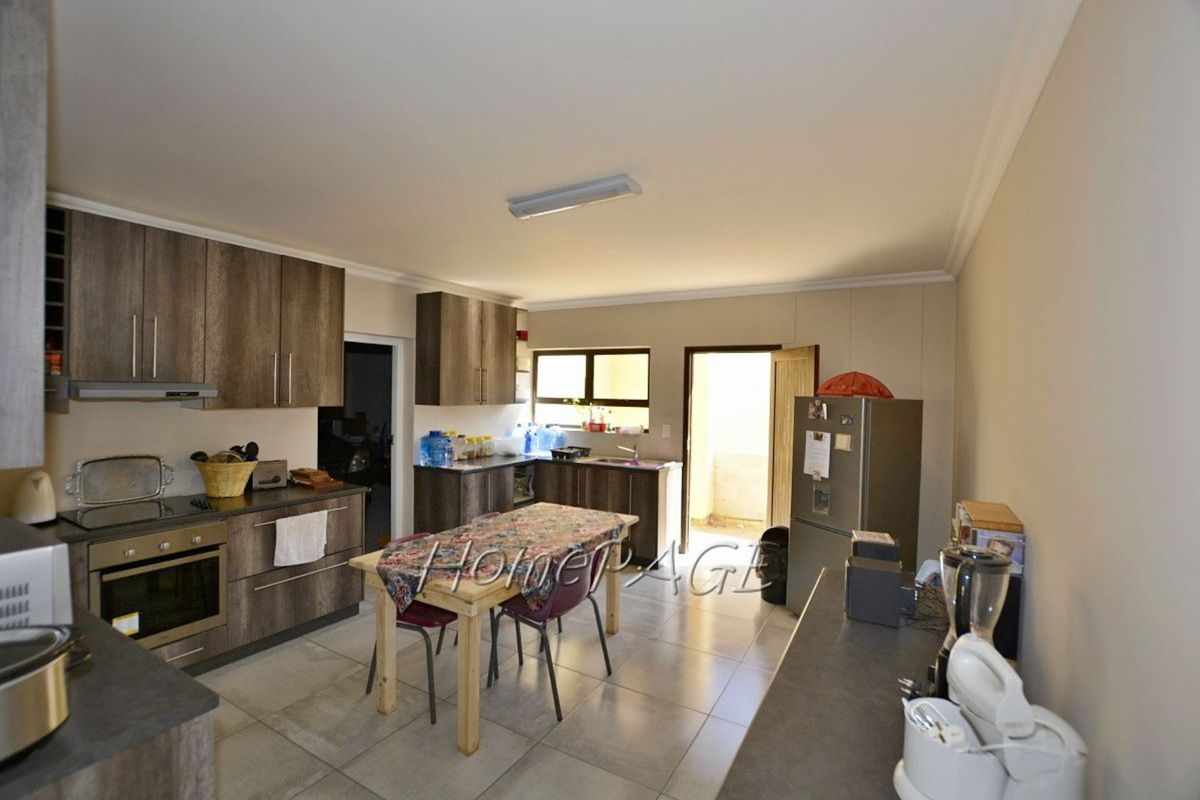 A functional kitchen featuring wood-look cabinetry, built-in oven, hob, extractor fan, and tiled flooring with direct access to an outdoor area.