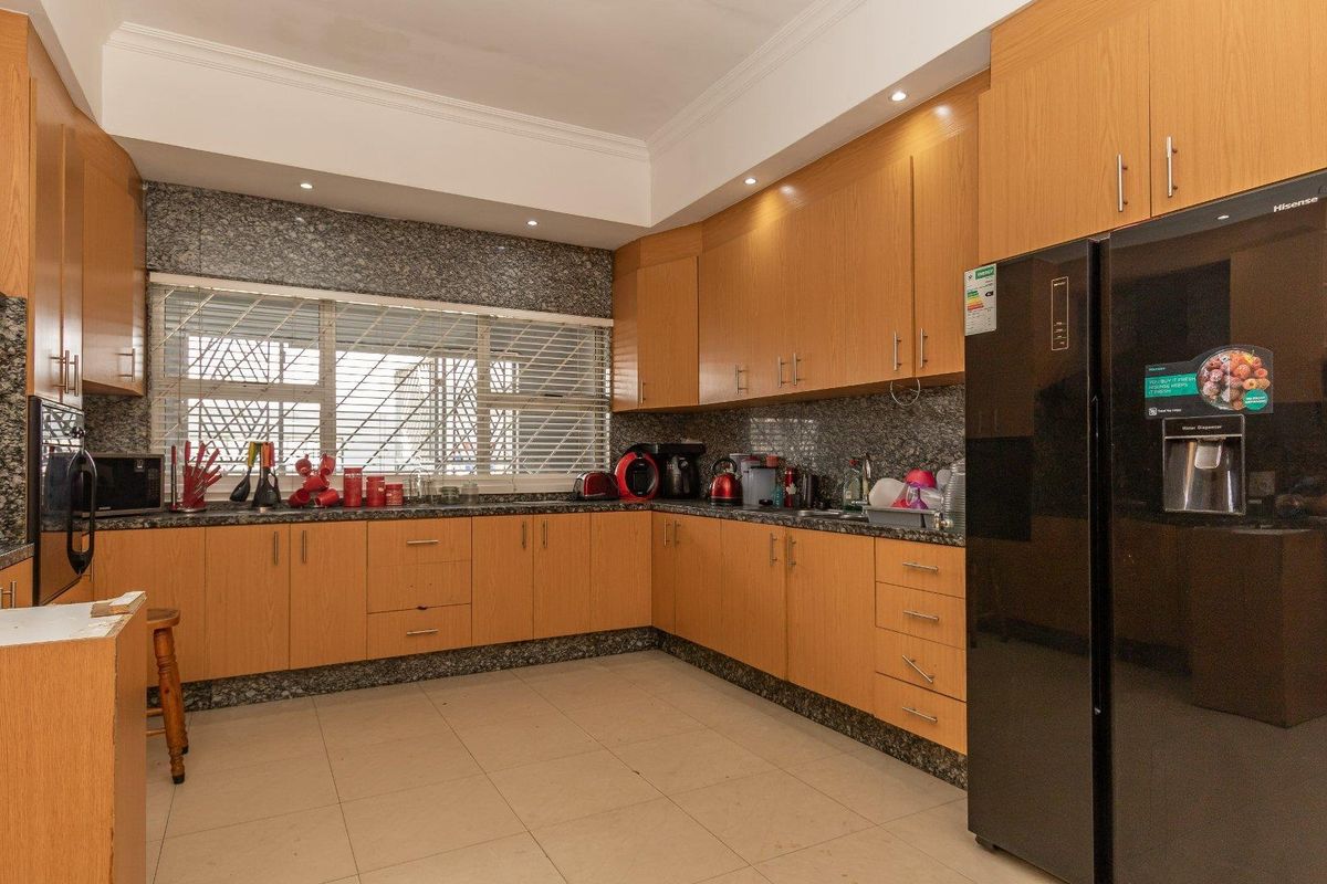 A functional kitchen featuring light wood cabinetry, granite countertops, tiled flooring, and recessed ceiling lighting.
