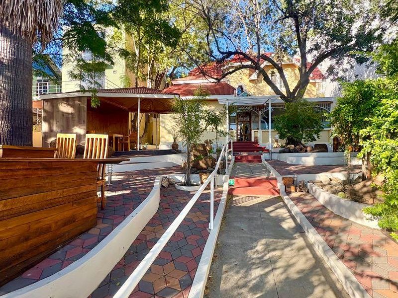 Front entrance view of the office property featuring a paved walkway with handrails, landscaped garden, and a covered patio area.