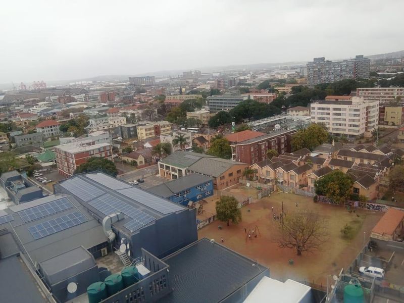 Elevated urban view overlooking the surrounding neighbourhood, featuring nearby residential buildings and commercial infrastructure with rooftop solar installations.