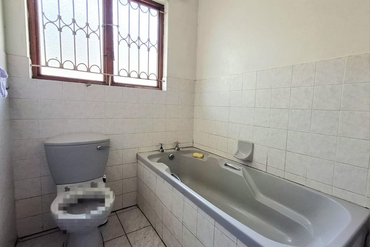 A functional bathroom featuring a bathtub, toilet, and tiled finishes, ready for modernization to enhance its appeal and value.