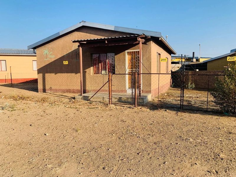 Front view of a single-story detached house featuring a metal roof, covered porch, and perimeter chain link fencing.