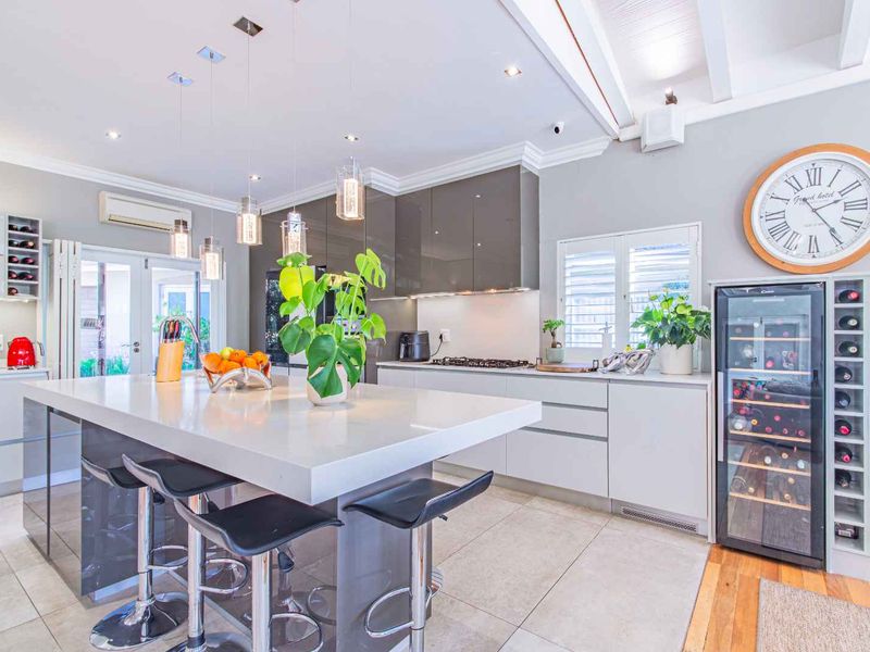 Modern kitchen featuring a large central island with stone countertops, high-gloss cabinetry, gas cooktop, and elegant pendant lighting in an open-plan layout.