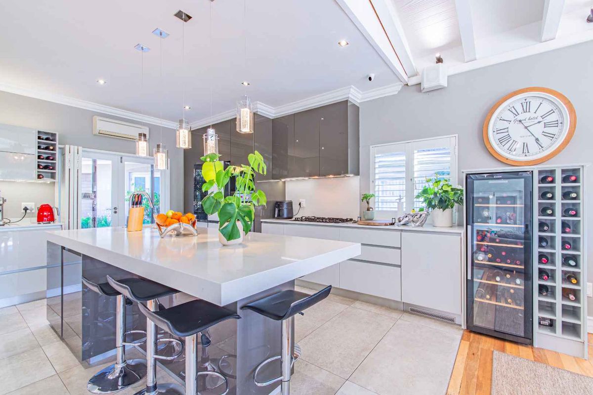 Modern kitchen featuring a large central island with stone countertops, high-gloss cabinetry, gas cooktop, and elegant pendant lighting in an open-plan layout.