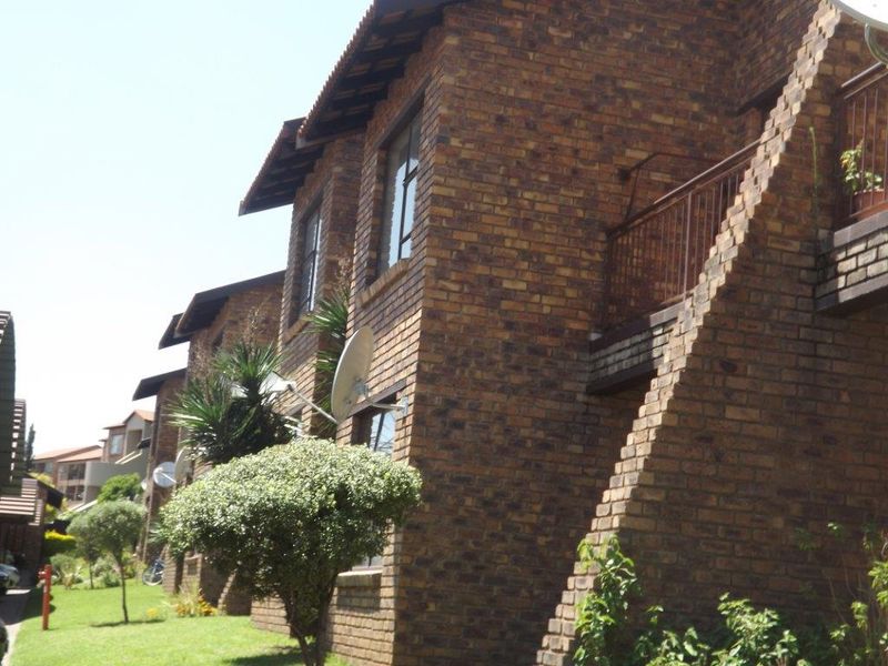 Exterior view of a multi-story apartment complex featuring face brick construction, tiled roofing, and private balconies.